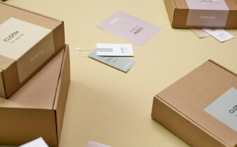 Simple and minimalist cardboard packaging boxes with labels on a yellow surface.